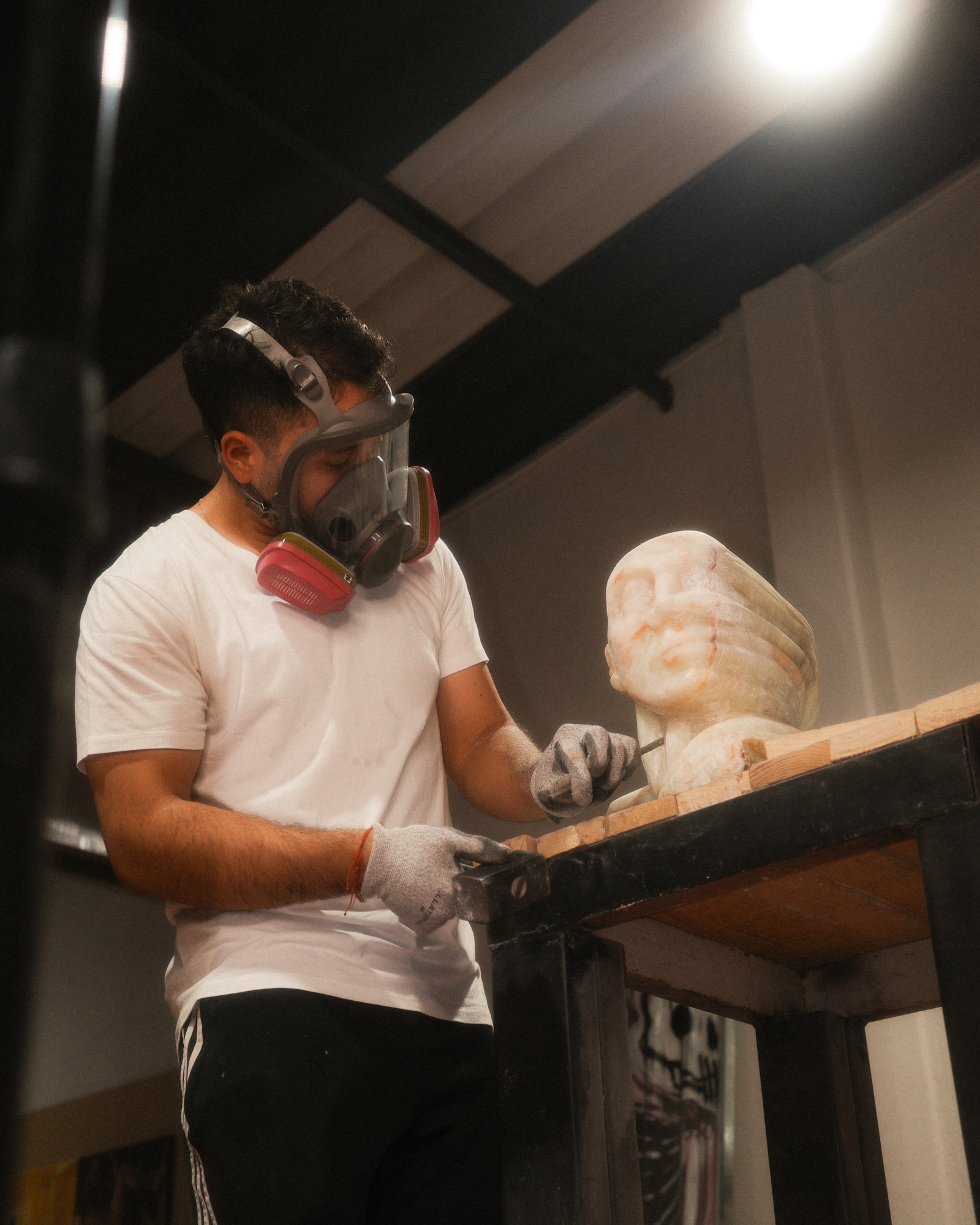 Leonel tallando un busto de mármol con careta